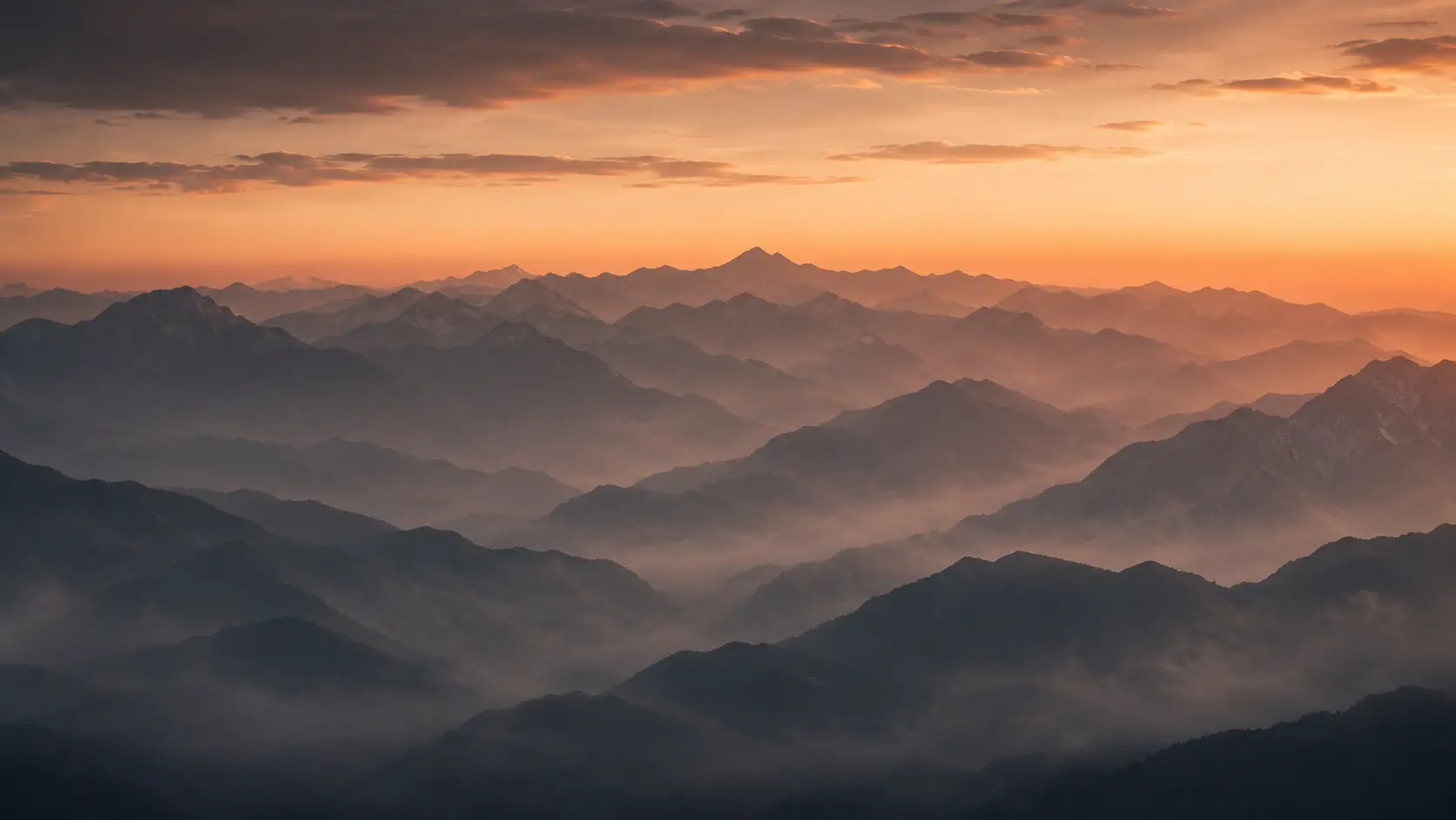 Layered mountain ridges fading into mist at dawn